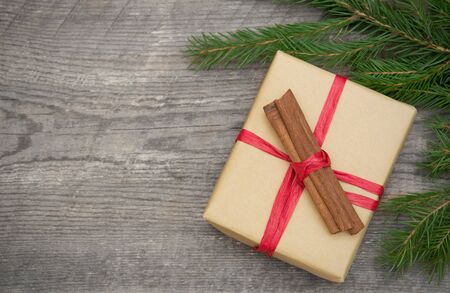 Gift box with cinnamon on wooden background with copy space, toned