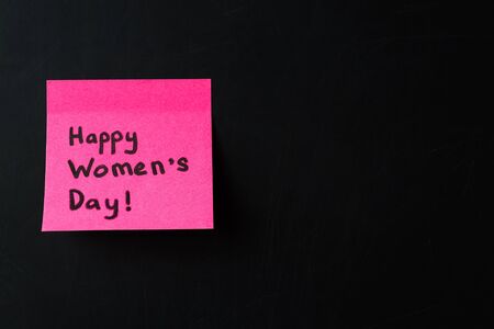Happy Women's Day. Pink sticker on black chalkboard, 8 march. Selective focus