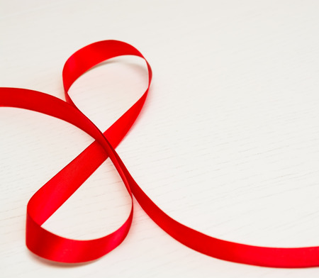 Happy Women's Day. Red gift ribbon in 8 digit shape over white wooden background. Selective focusの写真素材