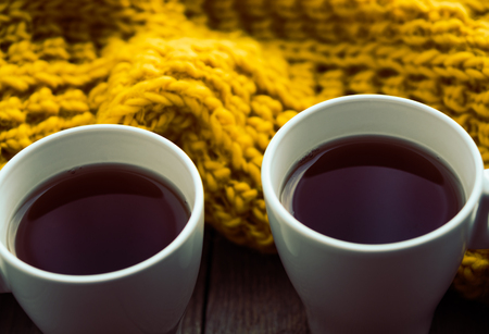Two white cups of tea and scarf on old wooden desk. Selective focus, tonedの写真素材