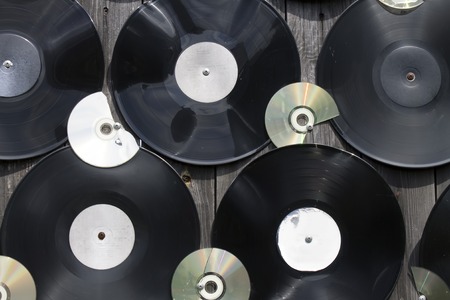 Old vinyl records and cracked compact discs are screwed to the fenceの写真素材