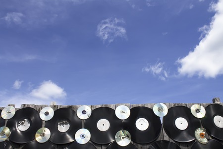 Vinyl and cd screwed to a fence against a blue sky backgroundの写真素材