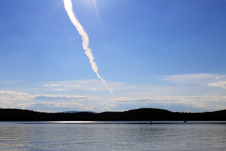 Trail from the plane in the sky above the lakeの写真素材