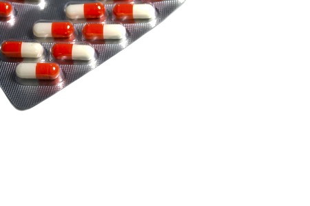 red and white capsules-pills, tablets in a plate on a white backgroundの写真素材
