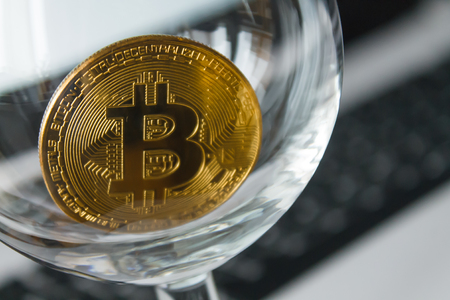 golden bitcoin in a glass on laptop backgroundの写真素材