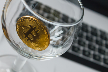 golden bitcoin in a glass on laptop backgroundの写真素材