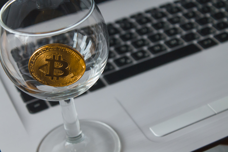 golden bitcoin in a glass on laptop backgroundの写真素材