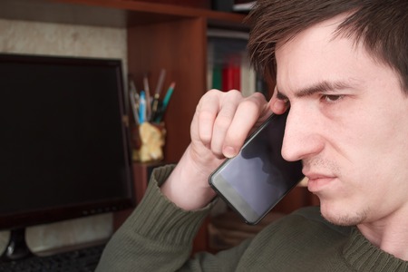 young guy talking on a black smartphone with a smileの写真素材
