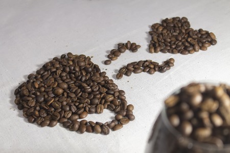 cup of coffee laid out of roasted coffee beans on tableclothの写真素材