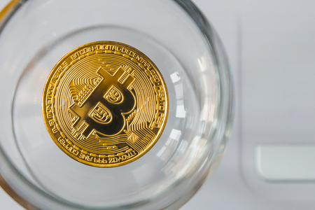 golden bitcoin in a cocktail glass on laptop backgroundの写真素材