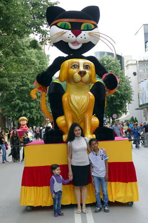 Gabrovo, Bulgaria May 19 2018.Traditional Carnival of Humor and Satire. Street art. A mother with two children poses for a picture in front of the cat - the main character of the carnival.のeditorial素材