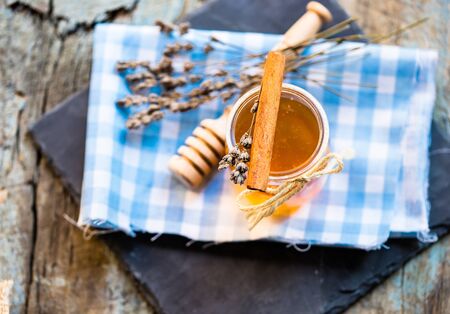 Jar of honey with dry lavender flower on a shabby wooden backgroundの写真素材