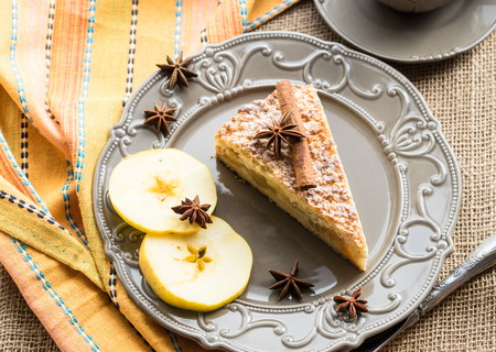Apple cake with slices of apple on a rustic plate with napkin and utensilsの写真素材