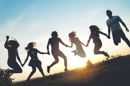 Group of people jumping outdoors; sunsetの写真素材