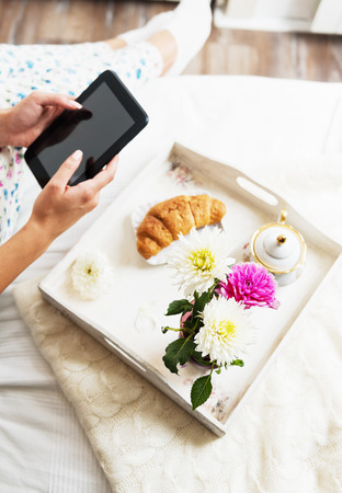 Woman using a tablet with breakfast in bed, detailの写真素材