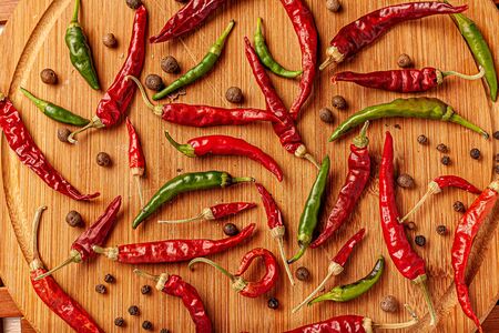 Red and green chili peppers on a wooden board.の写真素材