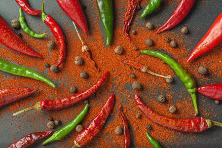 A lot of red and green pepper and pepper. Sprinkle paprika on a black background, top view.の写真素材