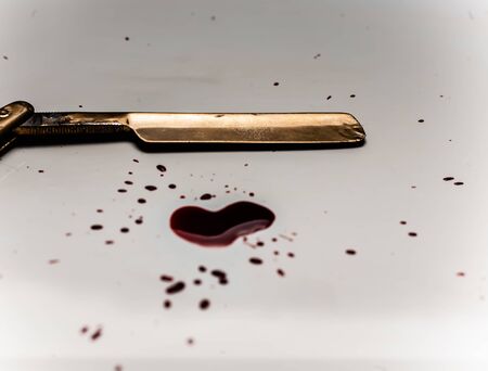 Dangerous razor bloodied on a light background. Razor with bloody smudges on the blade.の写真素材