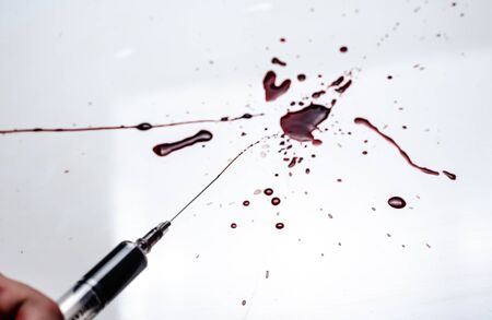 Syringe and blood splatter on a white background. A lot of blood and a syringe.の写真素材