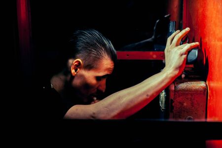 A man of criminal appearance in a payphone booth at night. Talking on the phone with a revolver and...