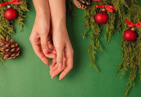 Christmas background with pine toys and female hands. Top view on a green background.の写真素材
