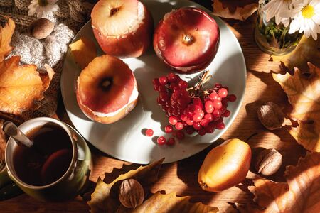 Autumn composition. Baked apples with cottage cheese, cranberries, tea and leaves on the table.の写真素材