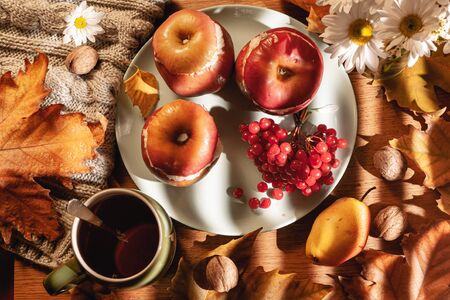 Autumn composition. Baked apples with cottage cheese, cranberries, tea and leaves on the table.の写真素材