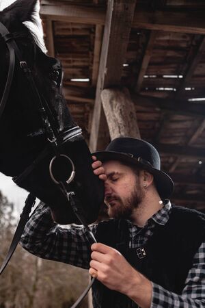 Portrait of a guy in a hat with a black horse.の写真素材
