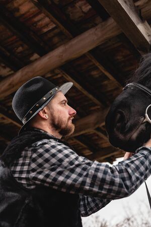 Portrait of a guy in a hat with a black horse.の写真素材
