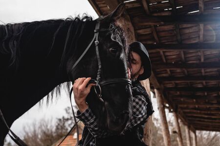 Portrait of a guy in a hat with a black horse.の写真素材