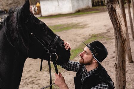 Portrait of a guy in a hat with a black horse.