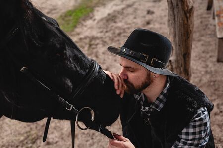 Portrait of a guy in a hat with a black horse.の写真素材