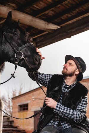 Portrait of a guy in a hat with a black horse.の写真素材