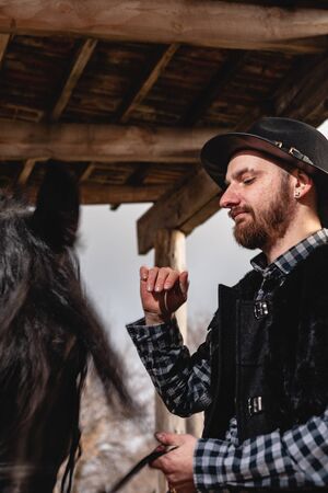 Portrait of a guy in a hat with a black horse.の写真素材