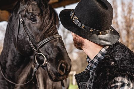 Portrait of a guy in a hat with a black horse.