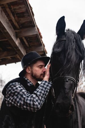 Portrait of a guy in a hat with a black horse.の写真素材