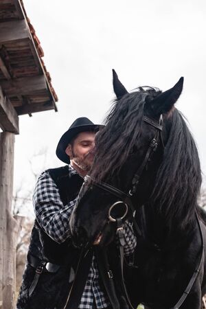 Portrait of a guy in a hat with a black horse.の写真素材