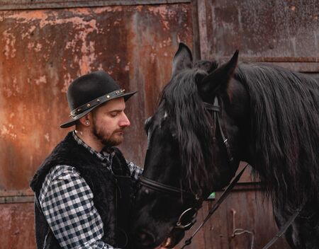 Portrait of a guy in a hat with a black horse.の写真素材