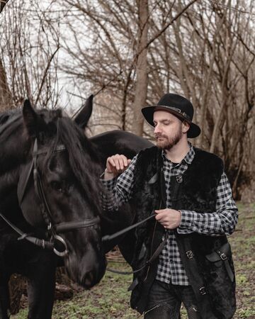 Portrait of a guy in a hat with a black horse.の写真素材