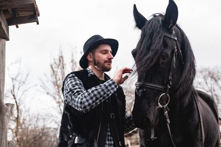 Portrait of a guy in a hat with a black horse.の写真素材
