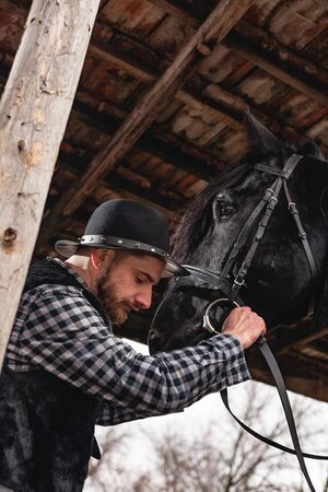 Portrait of a guy in a hat with a black horse.の写真素材