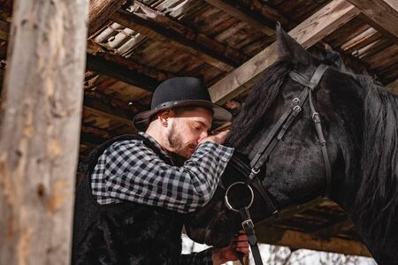 Portrait of a guy in a hat with a black horse.の写真素材