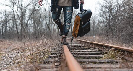 A guy in suede autumn boots on the railway. The concept of hiking, travel practical clothes, shoes.の写真素材