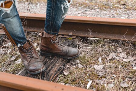 A guy in suede autumn boots on the railway. The concept of hiking, travel practical clothes, shoes.の写真素材