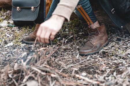 A stock photo of a man in nature sitting by a small fire, warming himself.の写真素材