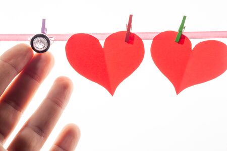 Red paper hearts on clothespins on a white background. Valentine's day and marriage proposal concept.の写真素材