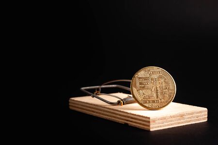 Bitcoin coin in a mousetrap isolate on a black background. Stock photo bitcoin news.