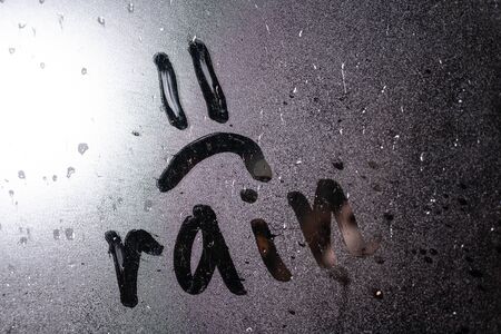Window with raindrops. Stock photo drawing the "sad smiley" on wet glass.の写真素材