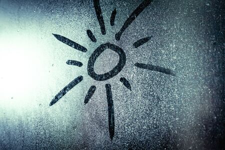Window with raindrops. Stock photo drawing the "sun" on wet glass.の写真素材