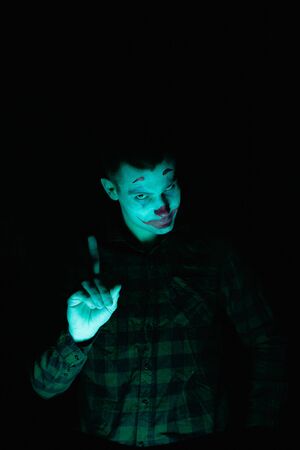 Close-up portrait of a joker man. Stock photo makeup joker in a horror room.